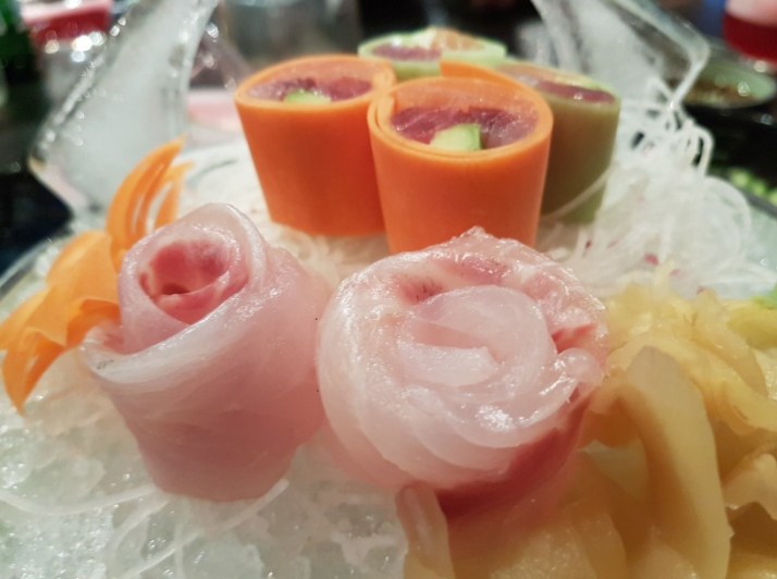 מבחר סשימי בשני סוגים - רול של מבחר דגים נאים קצוצים ועטופים בגזר ובמלפפון והשני, פרחי אוסוזוקורי לצד רוטב פונזו